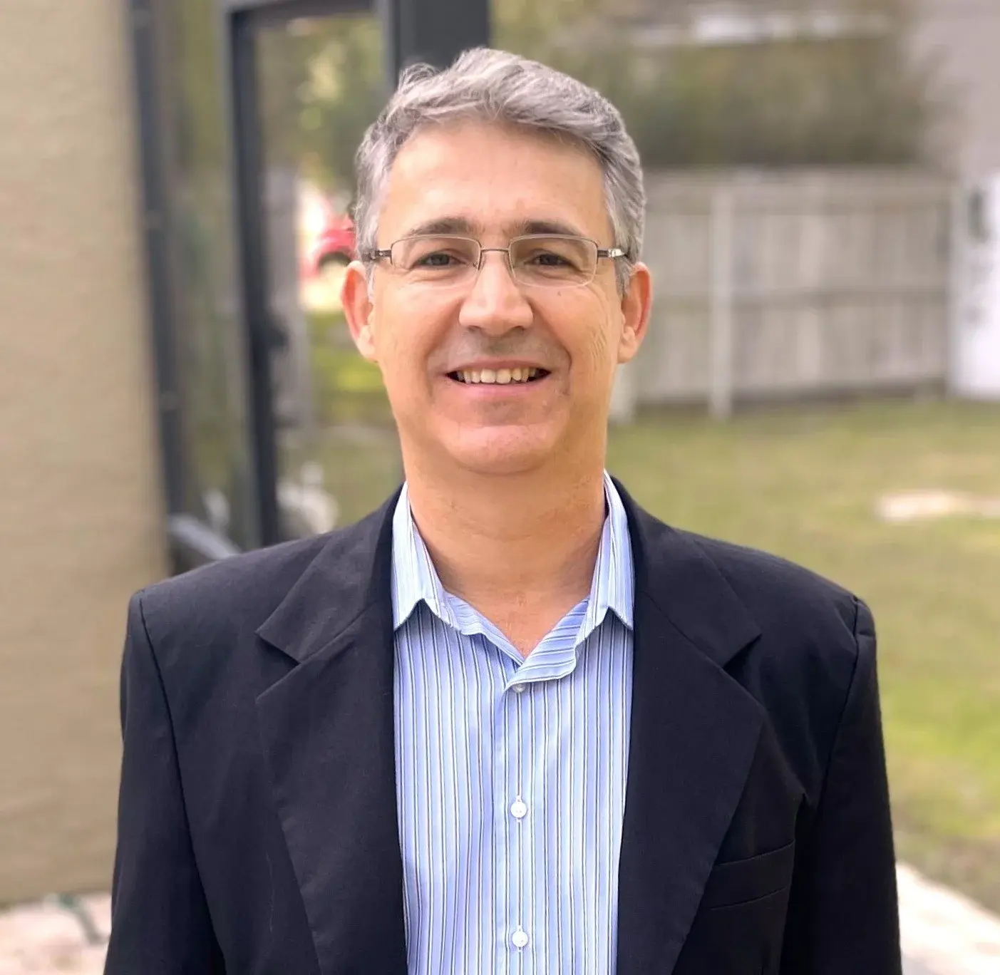 Marcio Sanchez, founder of Visible360, smiling outdoors in a dark blazer and striped shirt